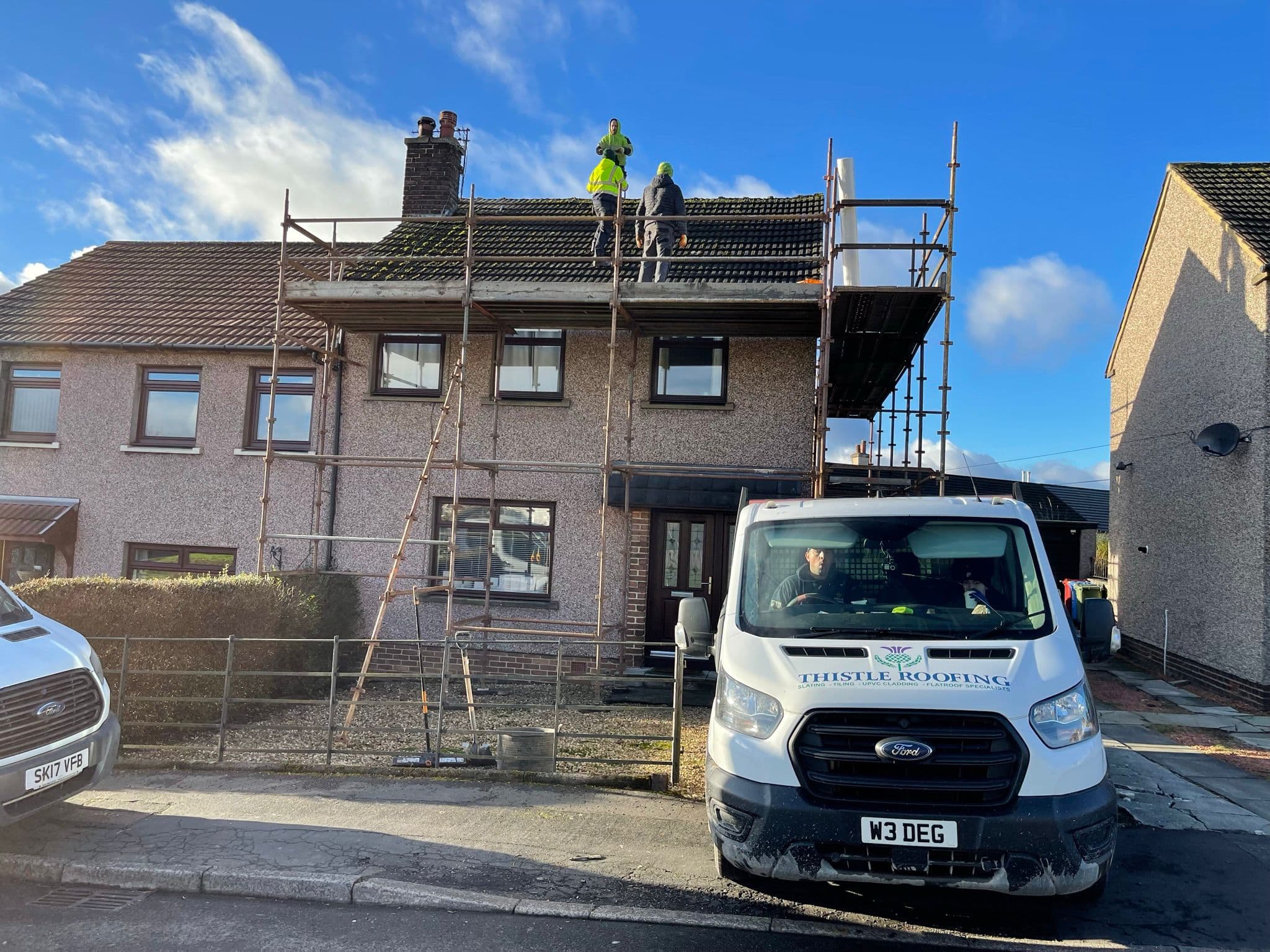 Thistle Roofing team working on a chimney stack from scaffolding, van parked outside